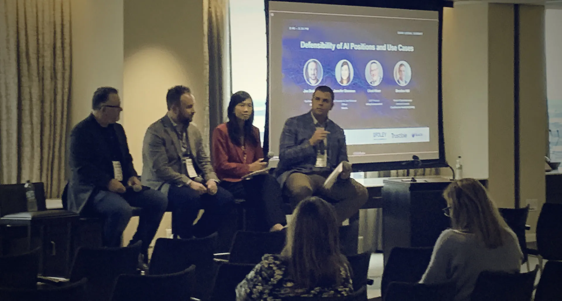 Four panelists seated on a low stage in front of a projected slide reading Defensibility of AI Positions and Use Cases, at the CHAI Legal Summit in Boston.
