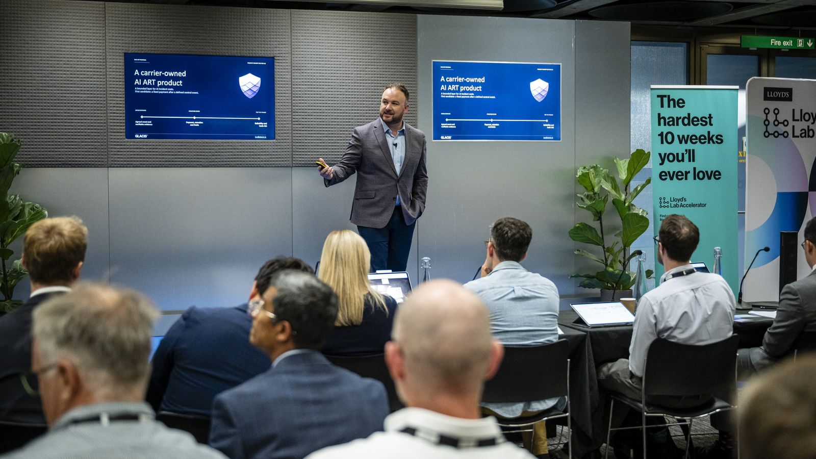 Joe Braidwood pitching at Lloyd’s Lab Pitch Day, beside the Lloyd’s Lab Accelerator banner