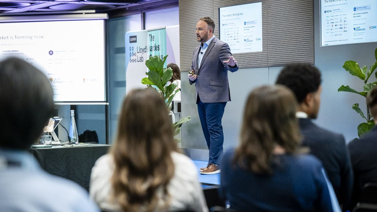 Joe Braidwood on stage at Lloyd’s Lab Pitch Day, with the slide The market is forming now
